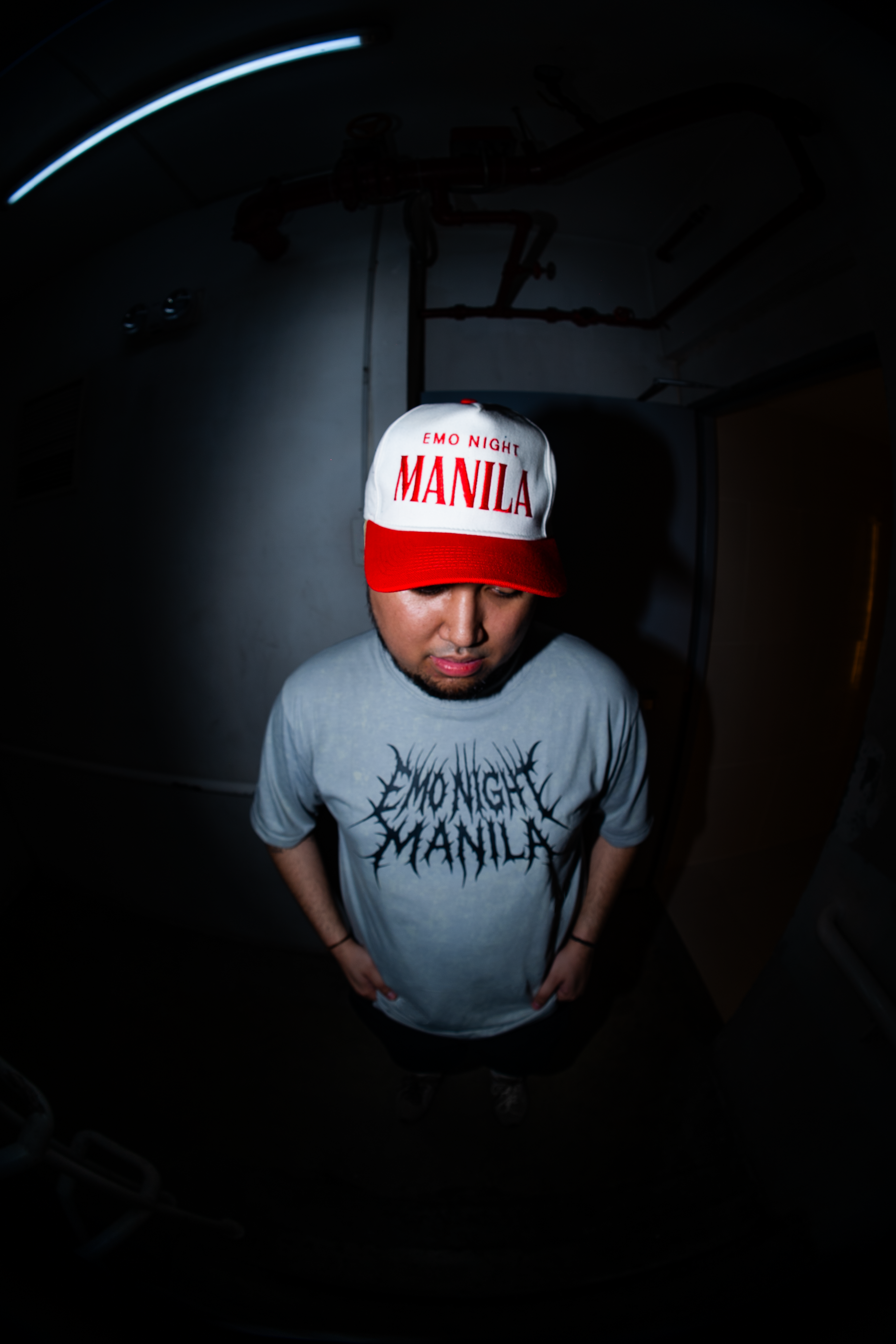 Person wearing a cap and t-shirt with text in a dark setting